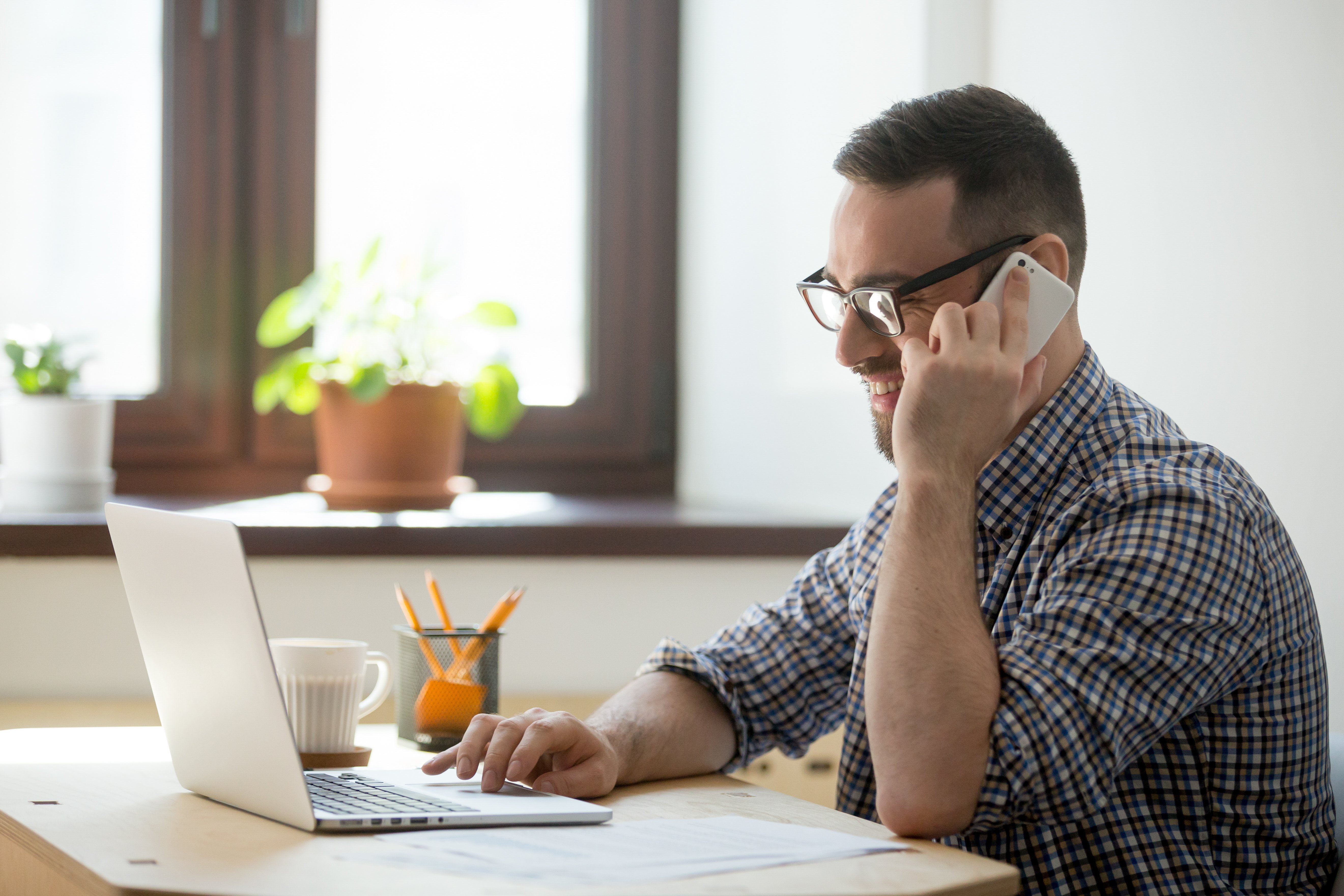 Homem falando ao telefone enquanto trabalha online