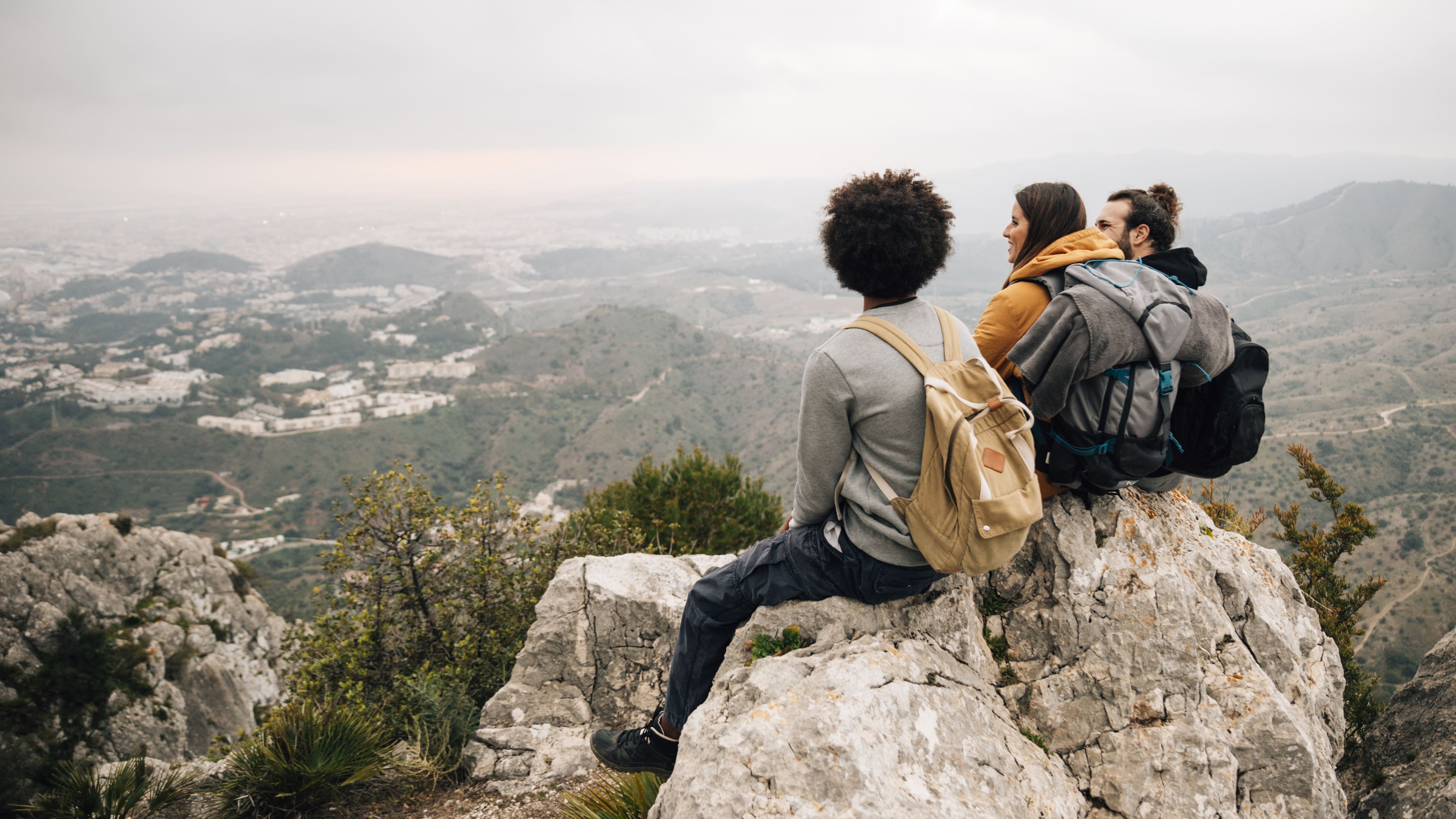 Três viajantes de férias sentados no topo da montanha fazendo turismo