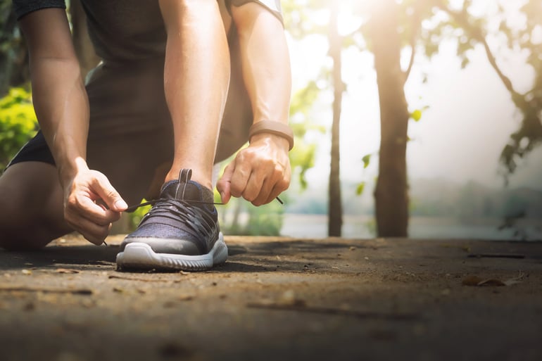 Atleta amarrando tênis em um parque representando artigos esportivos para vender