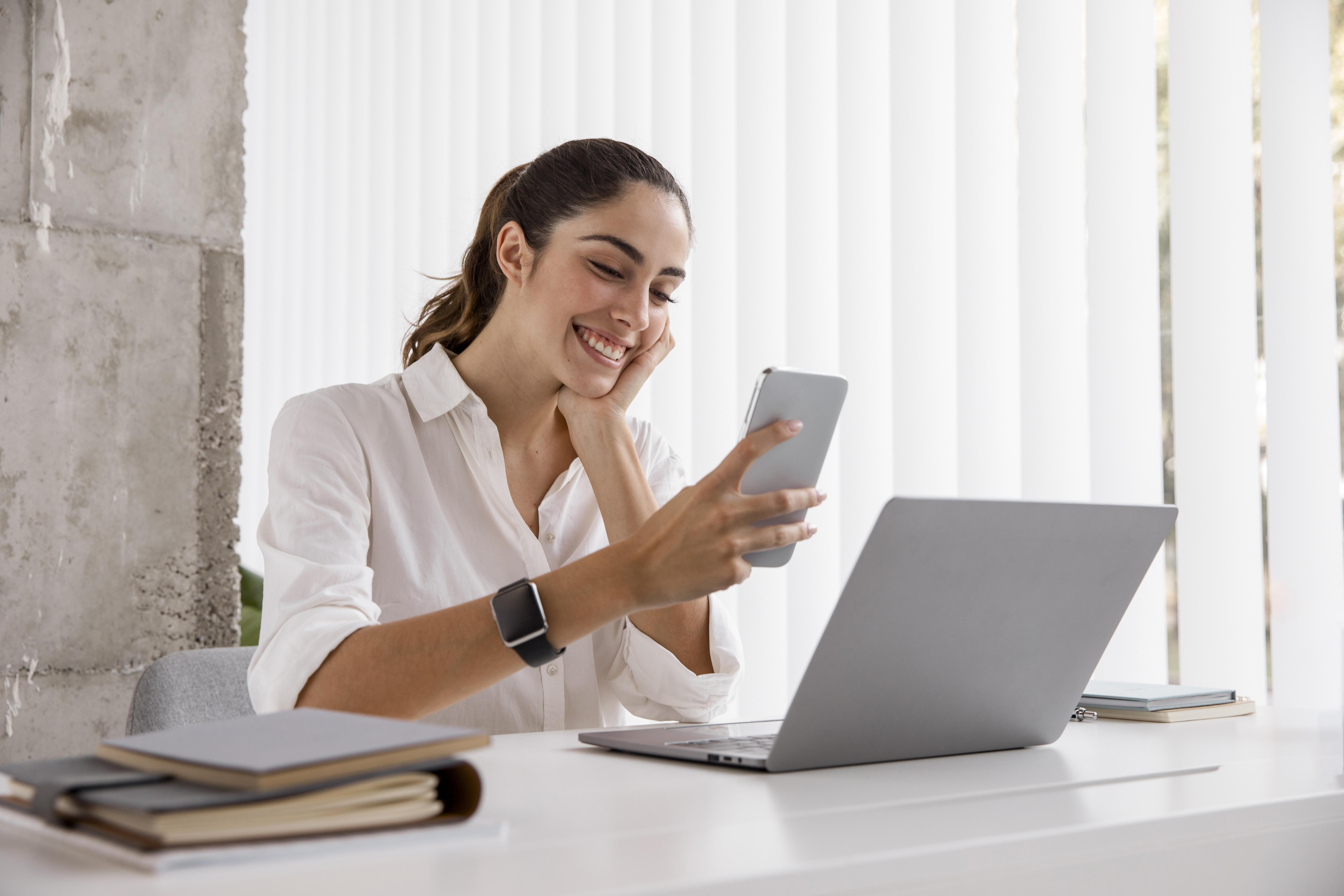 Mulher feliz aprendendo sobre Mercado Livre enquanto segura um celular