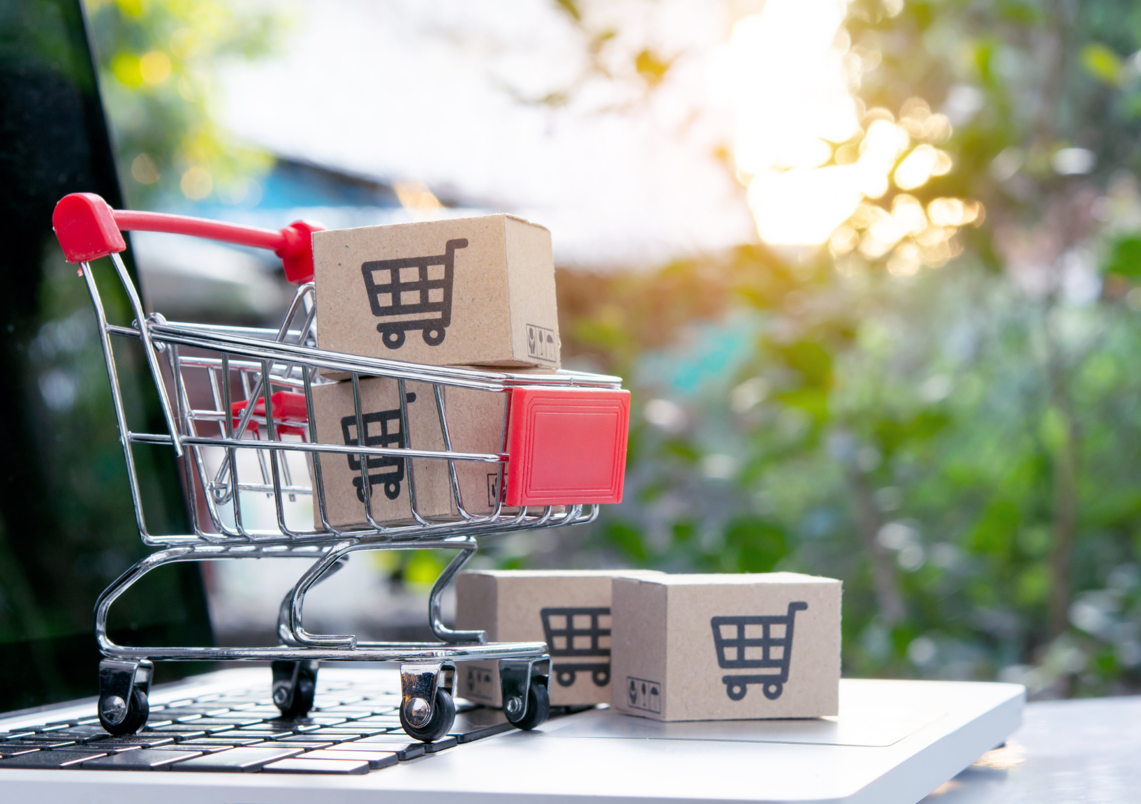 Carrito con cajas sobre una computadora que representa las ventas online