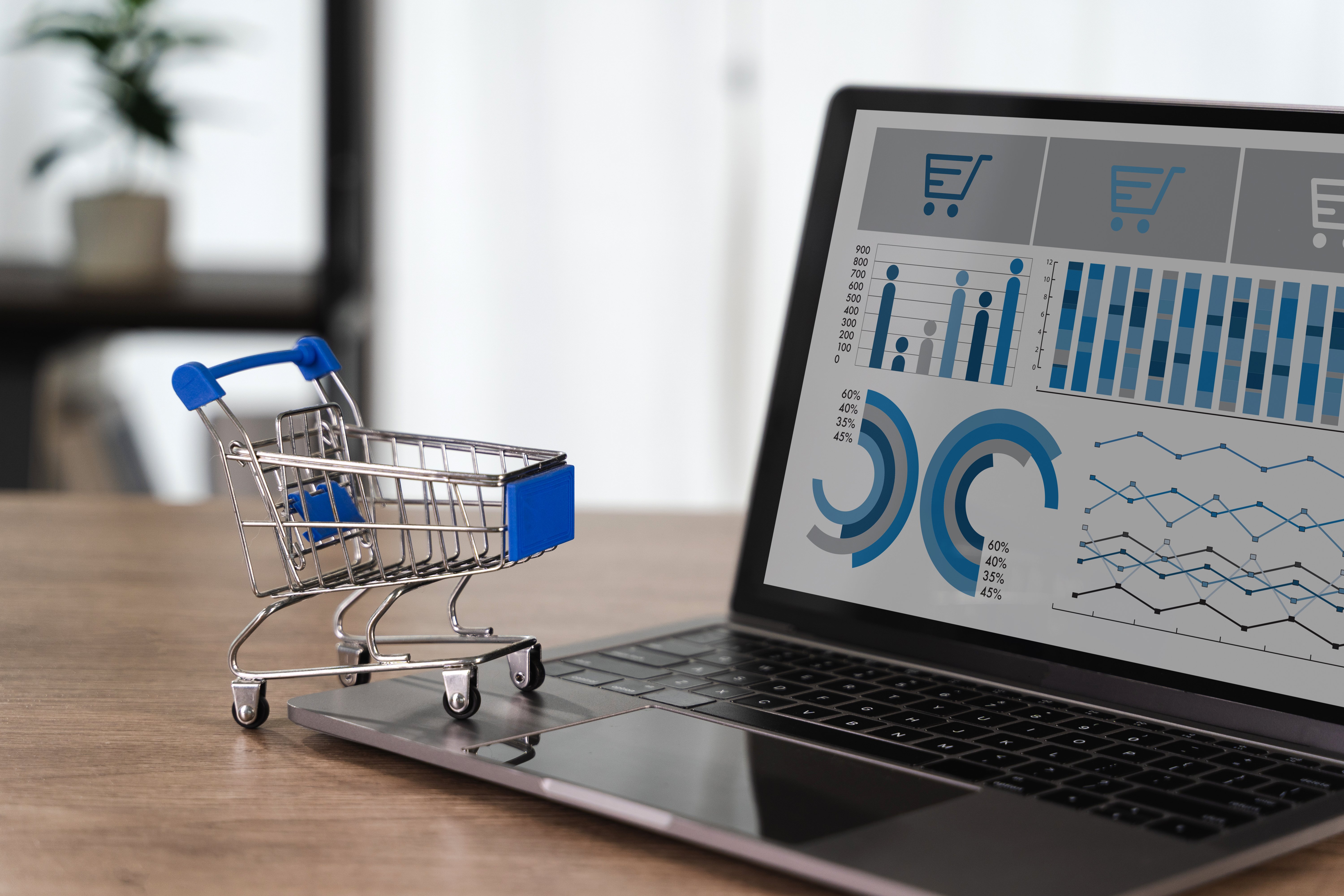 Carrito de compras frente a una computadora portátil con un panel de análisis de datos y gráficos de e-commerce