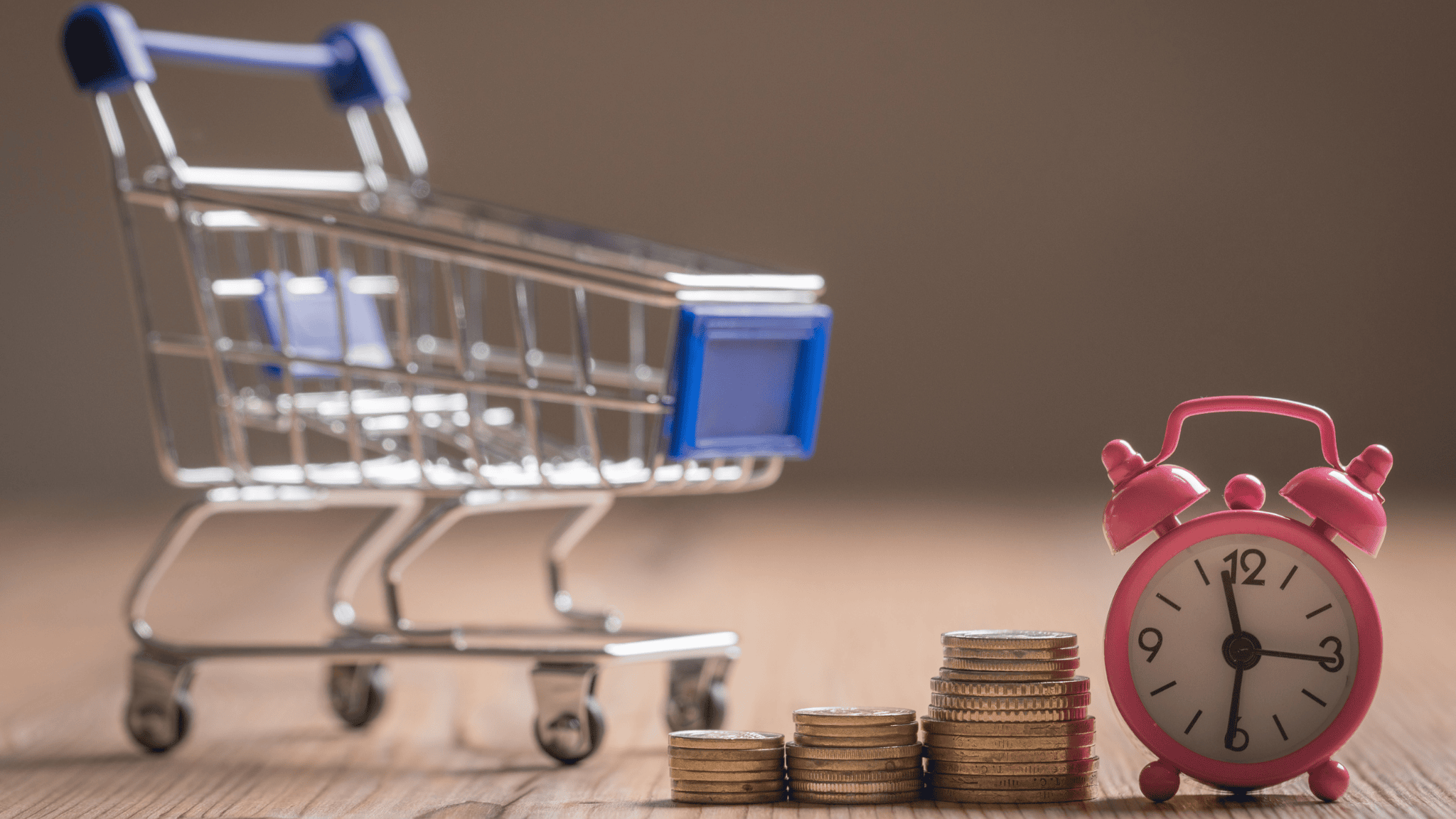 Imagem de um carrinho de compras em miniatura, moedas e relógio que representam os produtos que vendem rápido no e-commerce