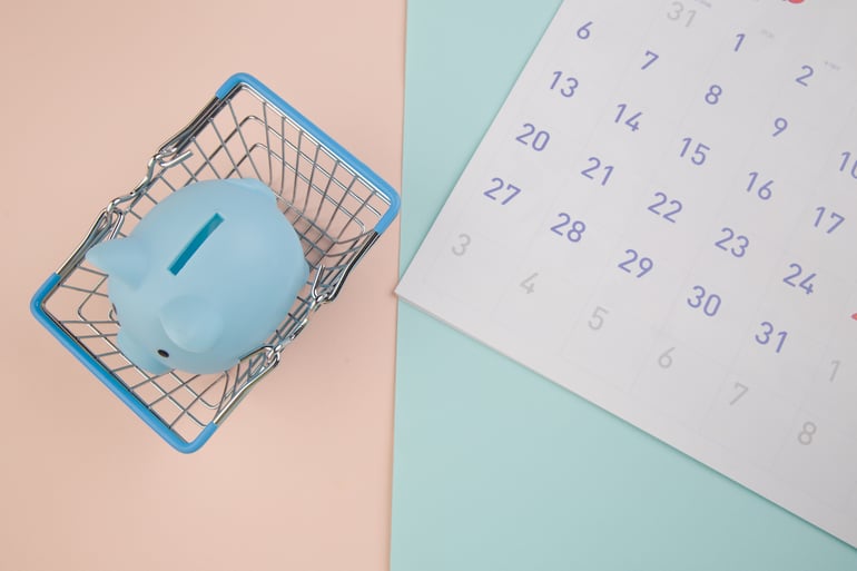 Cofrinho azul com calendário 2026, cesta de supermercado em um fundo colorido