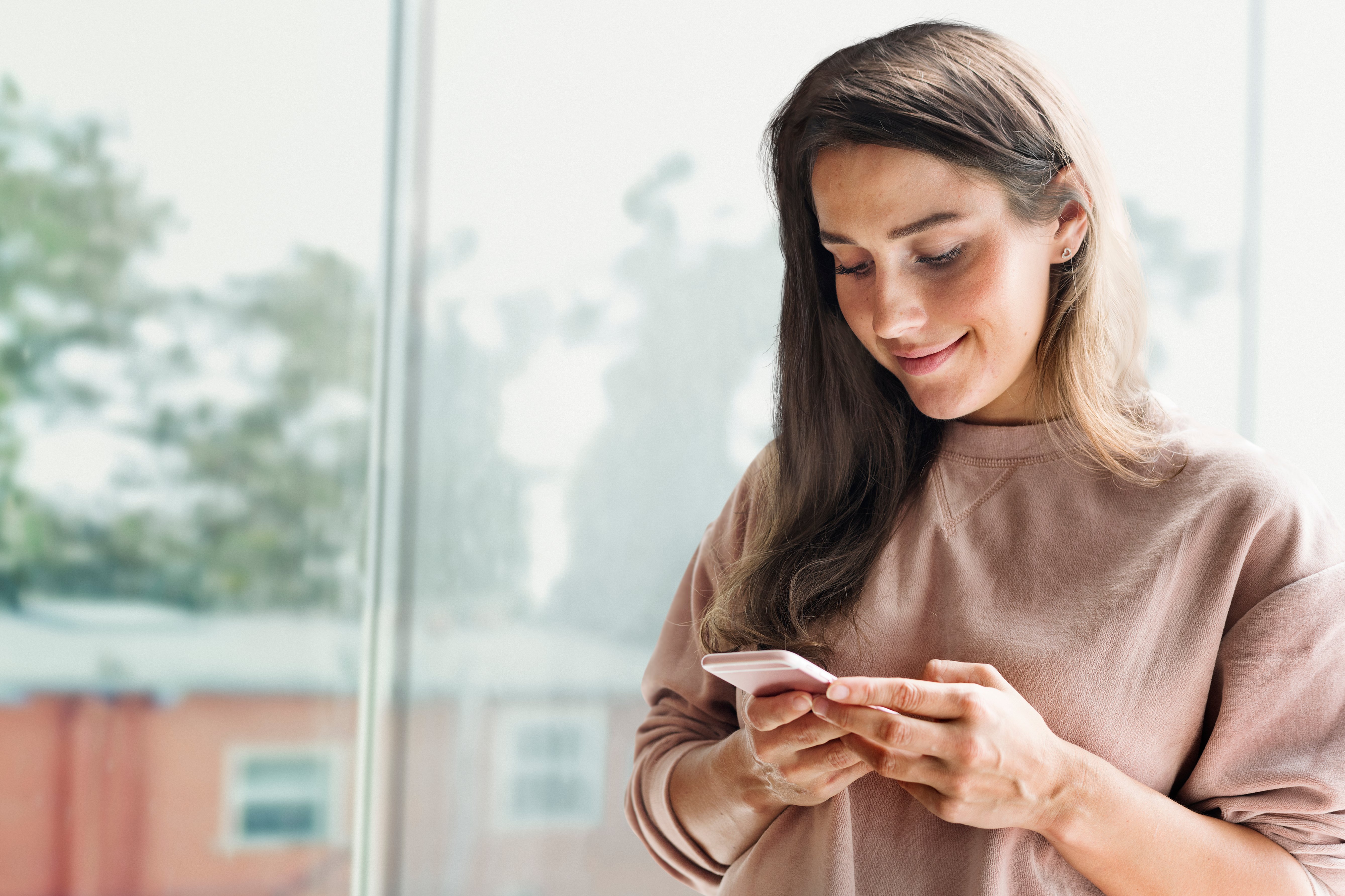 Mujer sonriente sosteniendo teléfono para ver su negocio online