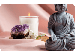 Estatueta de Buda, vela aromática, cravo branco e pedra energética sob tecido rosa