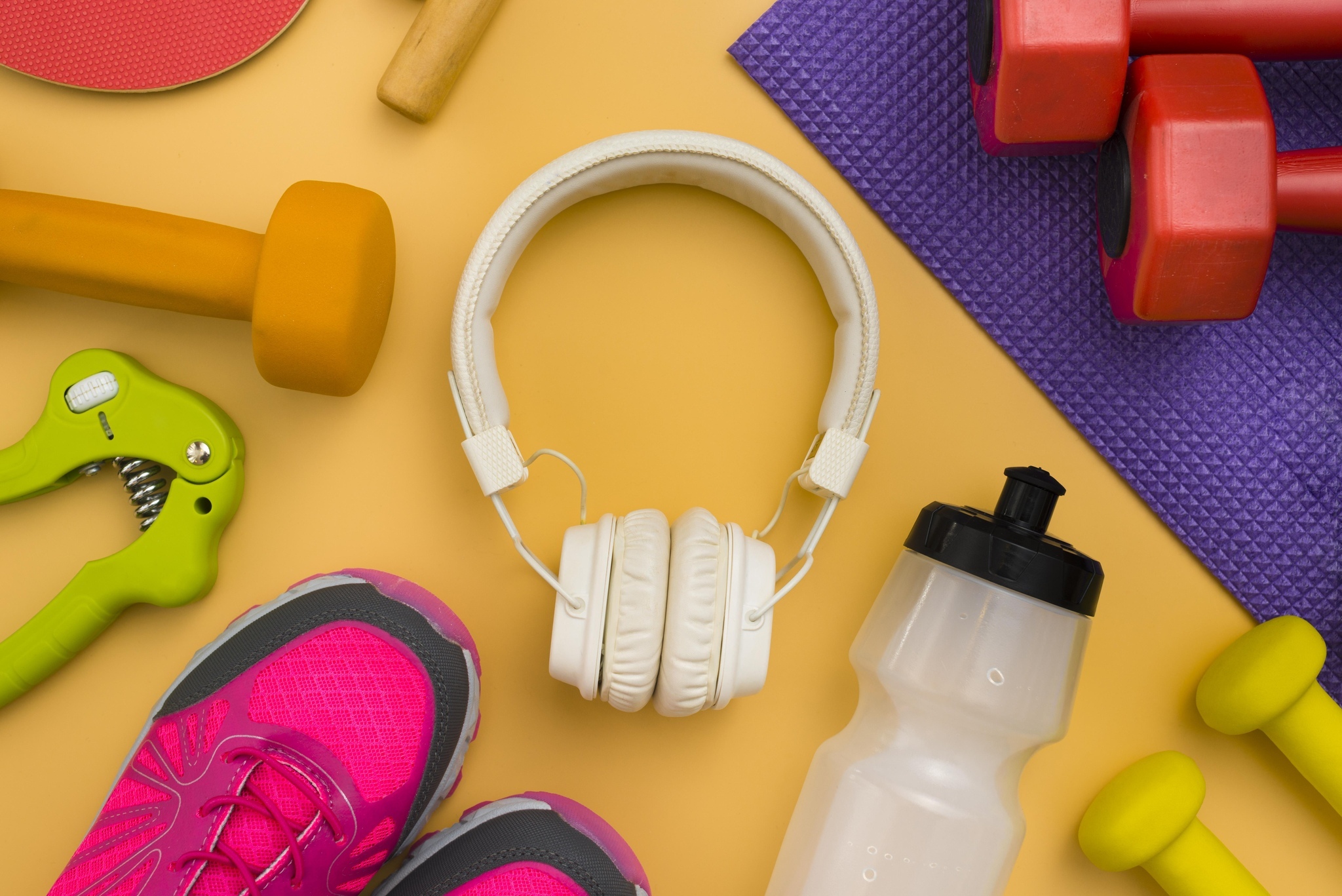 Fone de ouvido, pesos e tênis representando produtos fitness para treinar em casa