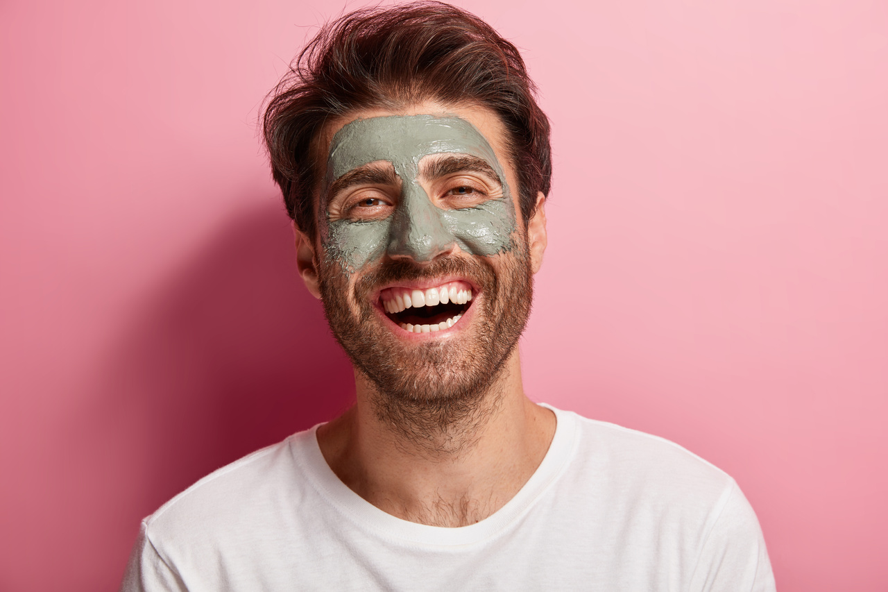 Homre sonriente usando productos de skin care