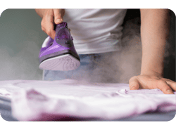 Homem com ferro de passar rouxo passando uma peça de roupa