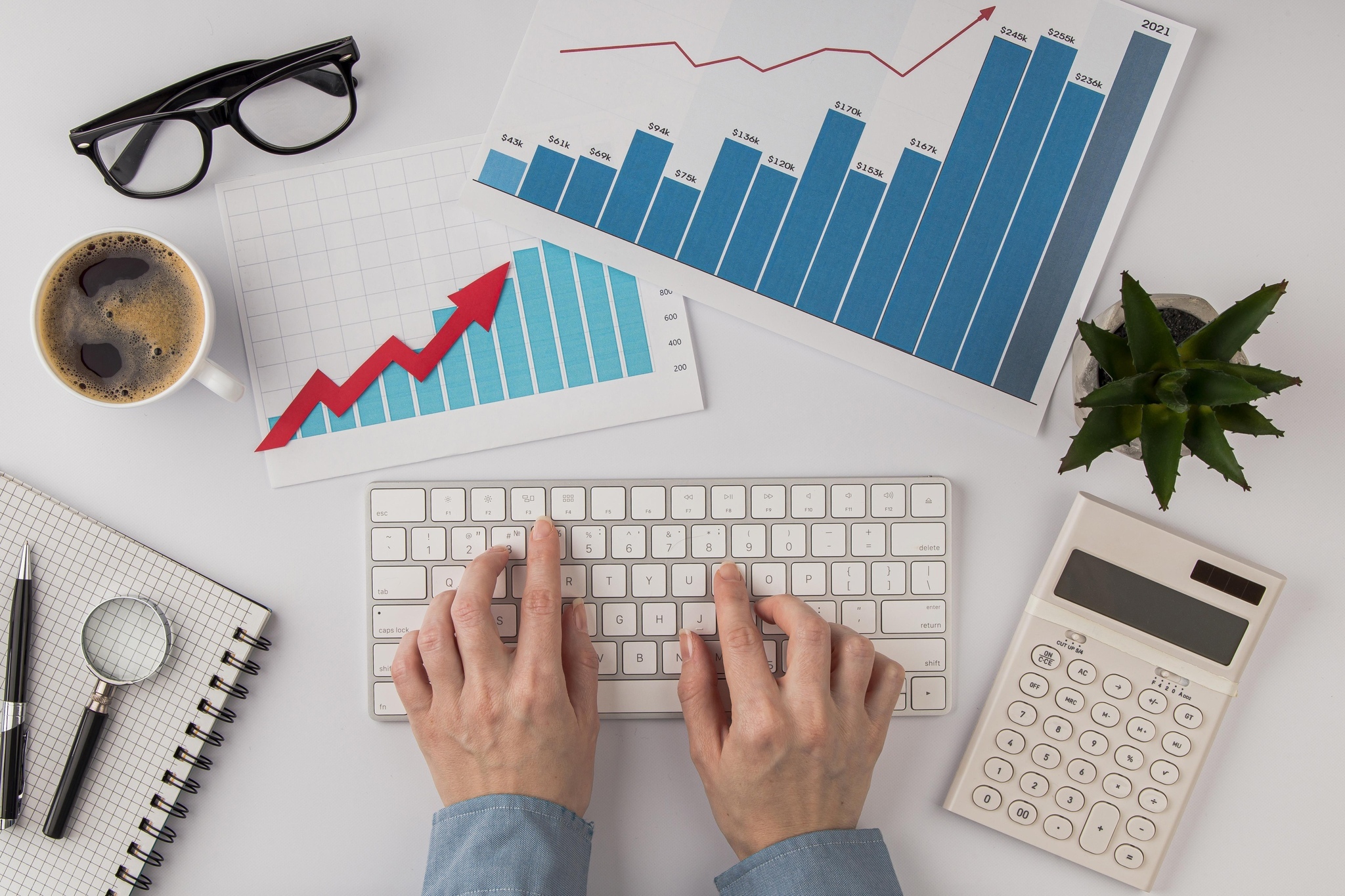 Imagem de uma mesa branca com gráficos impressos, teclado e outros elementos representando performance no e-commerce