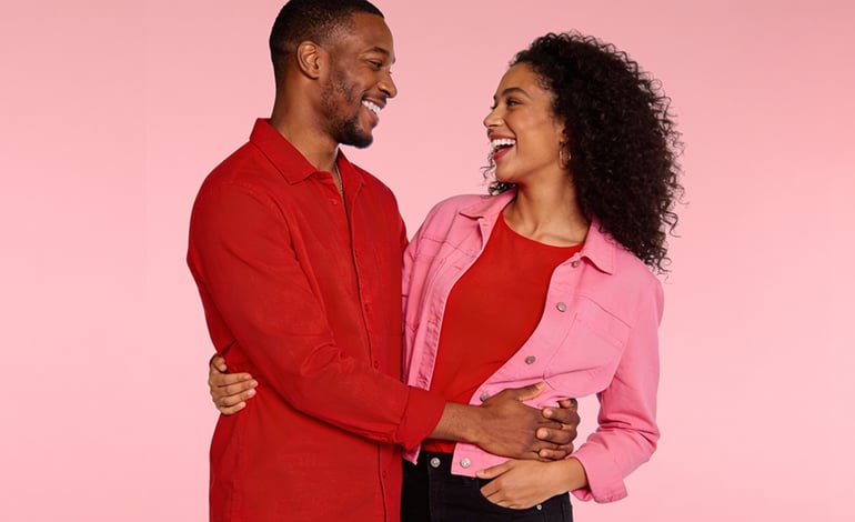 Casal diante de uma parede rosa, simbolizando o Dia dos Namorados