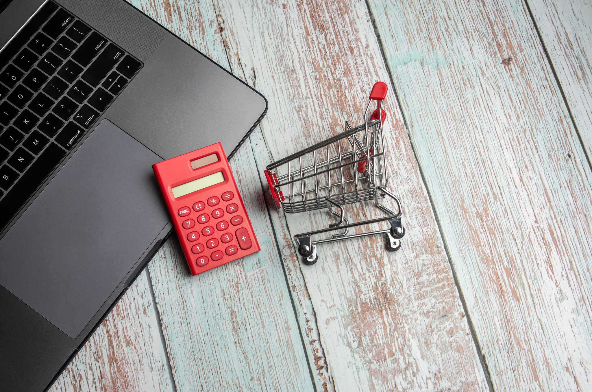 Laptop, calculadora e carrinho de compras representando gestão e controle de preços no e-commece