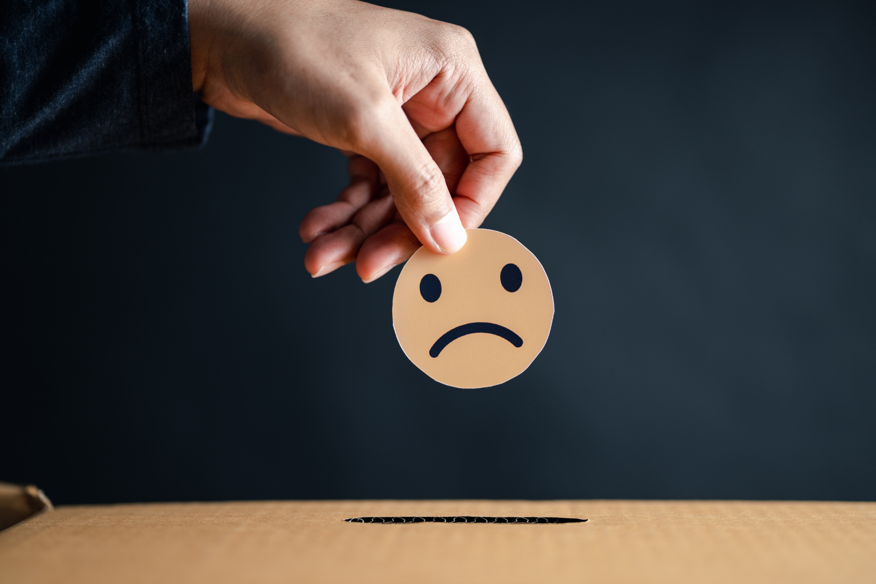 Mano sosteniendo un emoji de cara triste que representa la baja reputación de un negocio