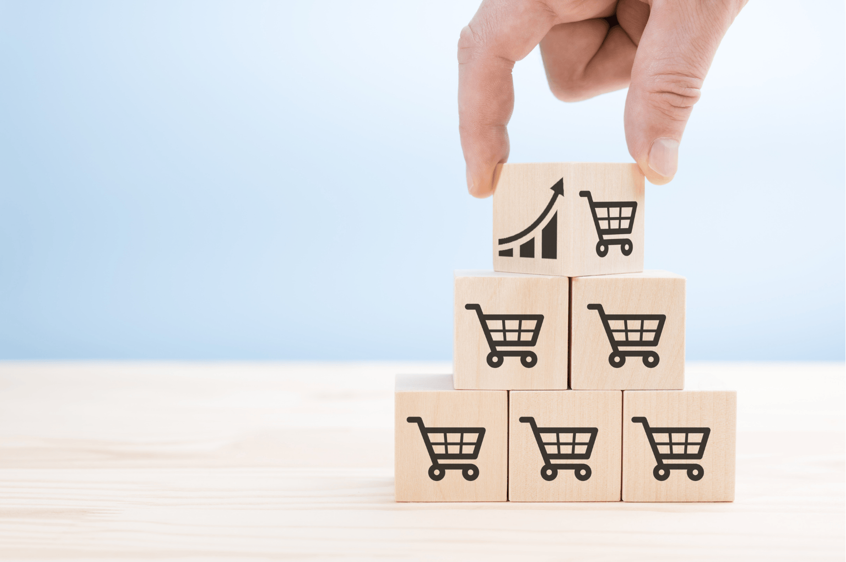 Manos generando una pirámide con cubos con carritos de compra representando la tasa de conversión