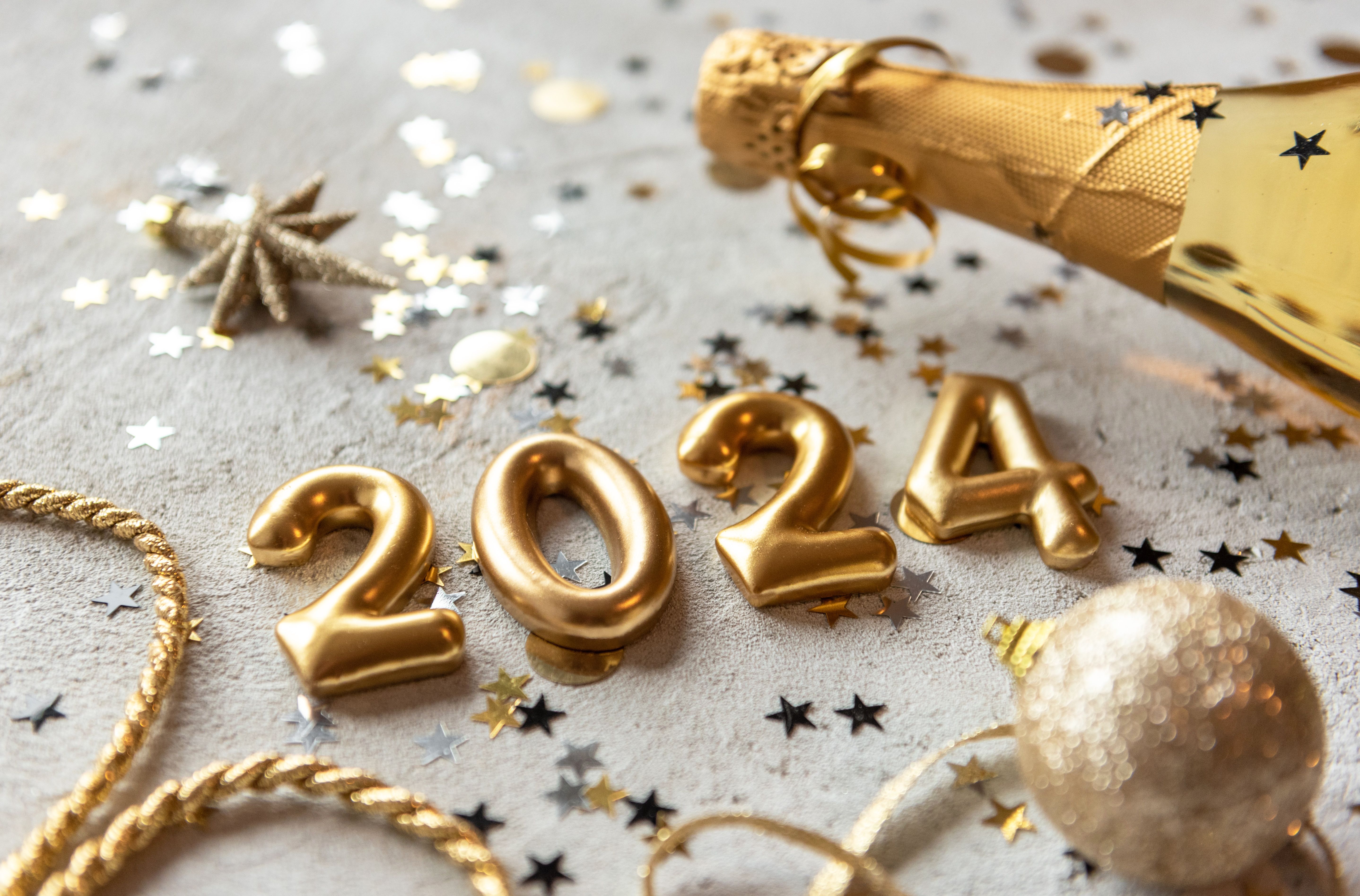 Números dourados formando 2024 com confete e garrafa de champanhe.jpg