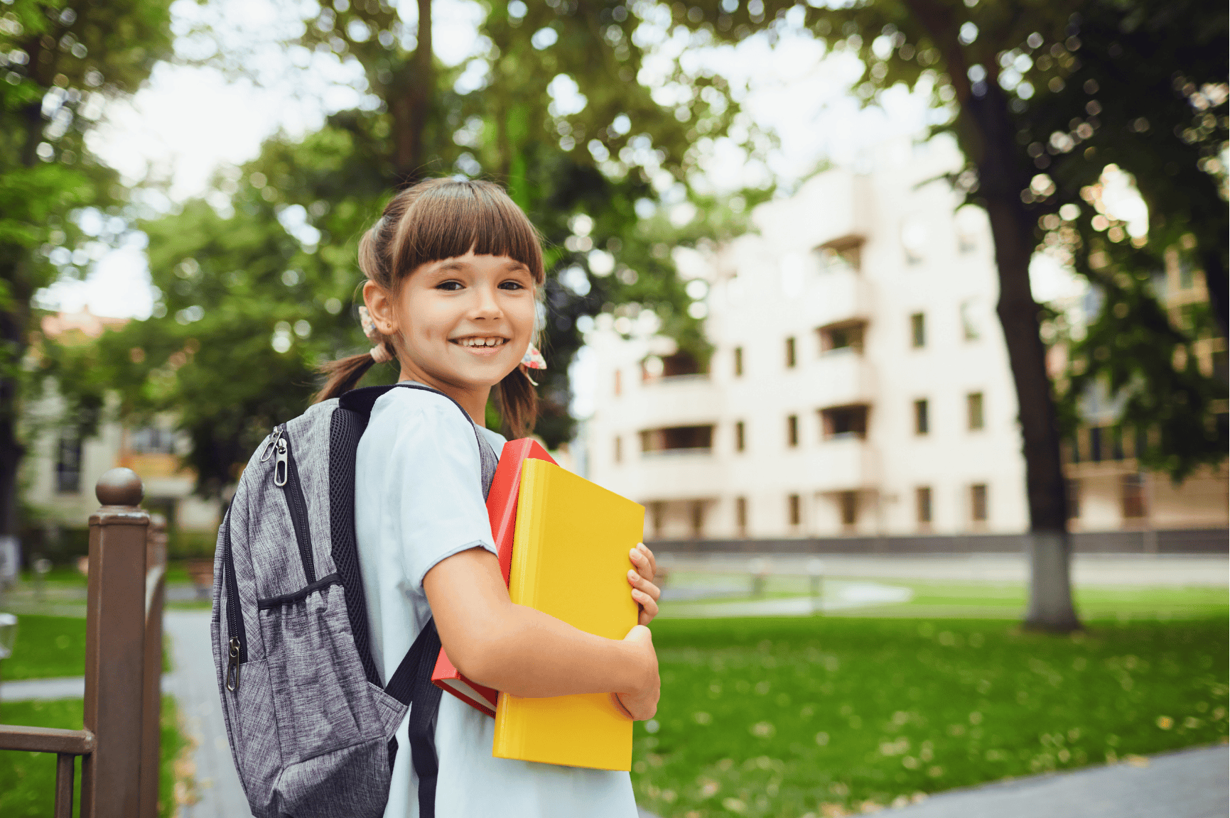 Niña con útiles escolares en el ingreso a una institución educativa representando el regreso a clases