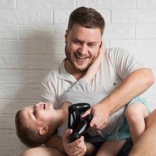 Pai e filho jogando videogame com gamepad e rindo