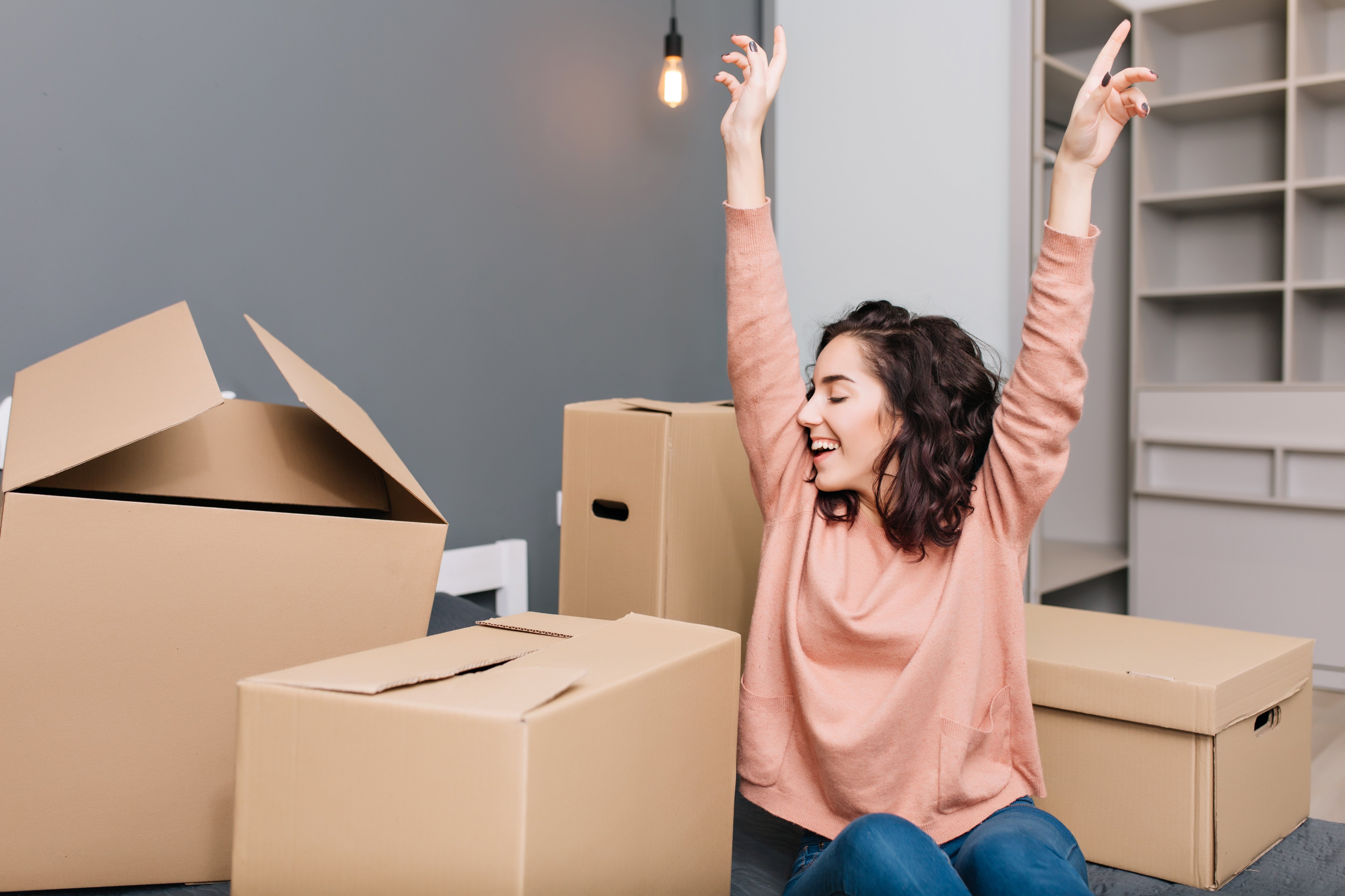 Mujer feliz y sentada con cajas de paquetería a su alrededor