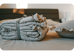 Set de roupas de cama beige aconchegante com detalhes arrufados cuidadosamente dobrados e colocados em uma cama em um quarto calorosamente iluminado Destaca temas de conforto, elegância e decoração de casa minimalista