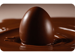 Um ovo de chocolate sobre chocolate derretido eem uma tigela