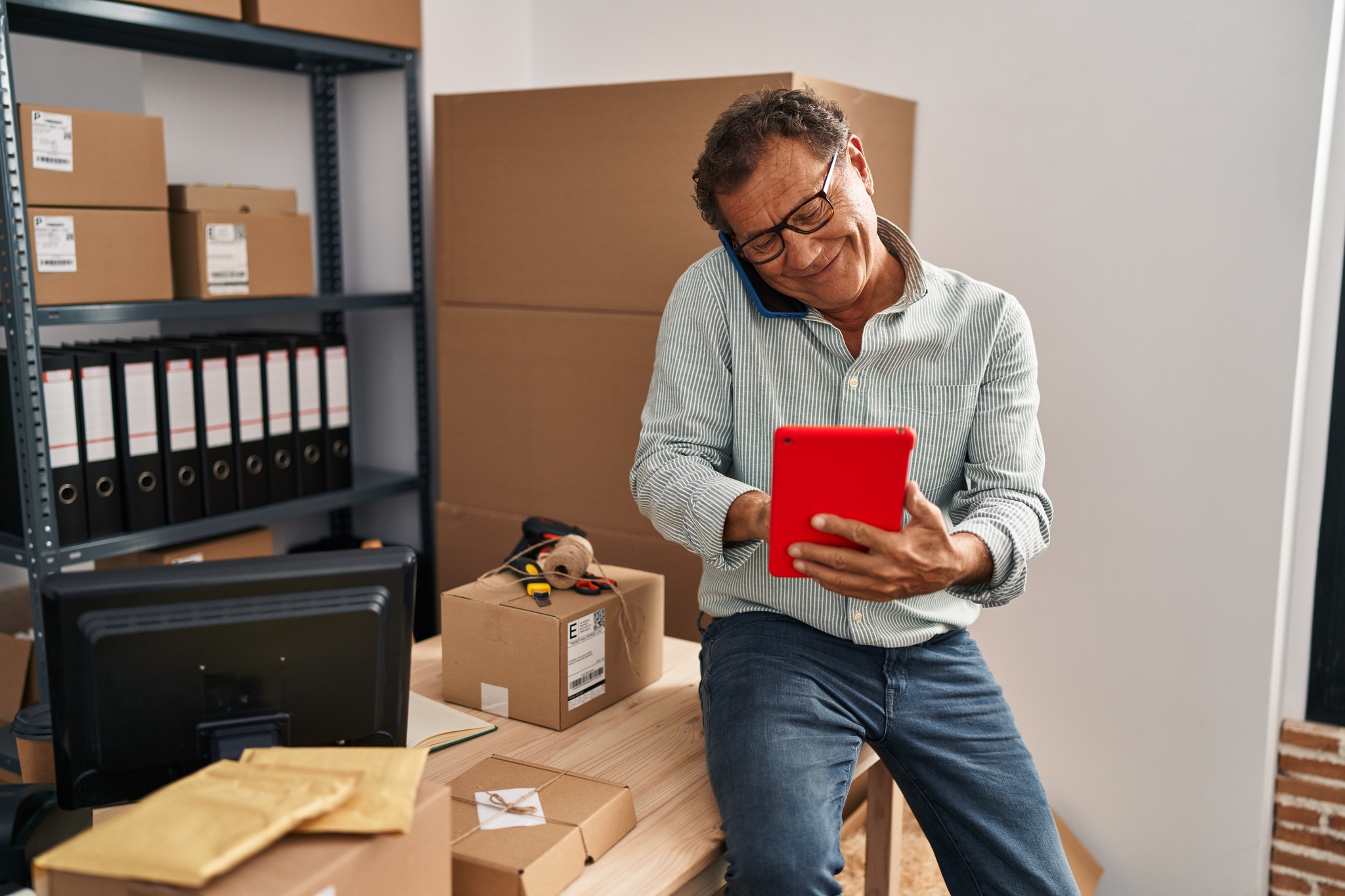 Vendedor de e-commerce falando ao telefone enquanto lê em um tablet as tendências para o Fim de Ano 2025